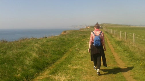 A female walker on the coast path near Burton Bradstock on a sunny day in early April